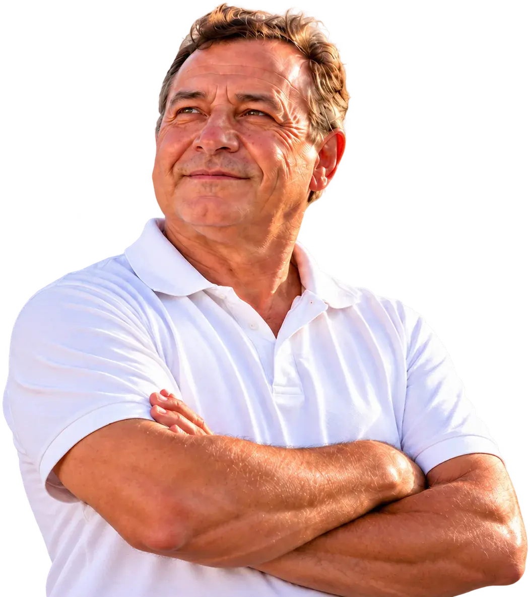 Motorista de camisa polo branca, de braços cruzados, à frente de um caminhão